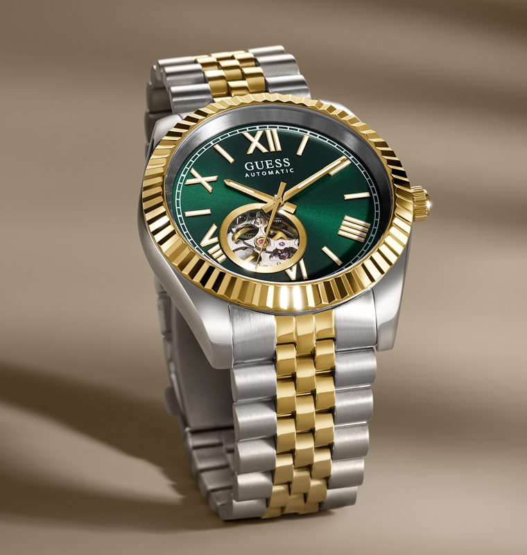 Guess watch with green dial and two-tone metal strap on a brown background