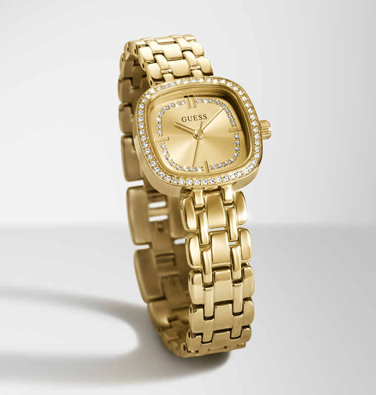 Gold-tone GUESS women's watch with a square bezel set with clear crystals, a gold dial with crystal hour markers, and a matching gold-tone link bracelet, shown on a light gray background.