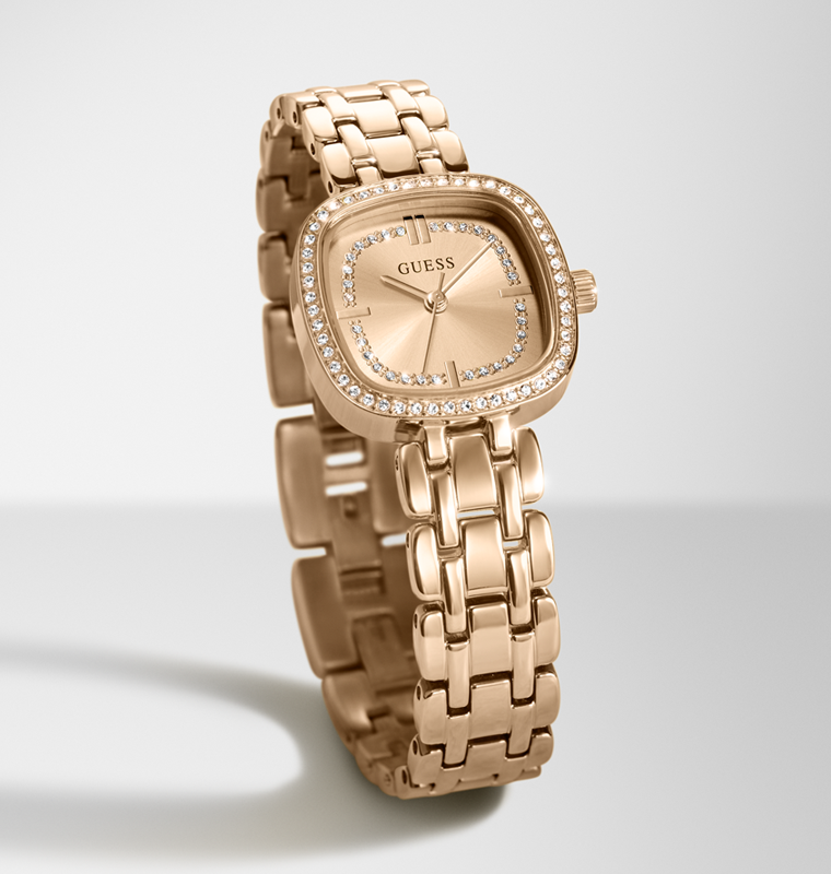 A rose gold GUESS women's watch with a square bezel set with clear crystals, a matching crystal-embellished dial, and a multi-link bracelet, shown on a light gray background.