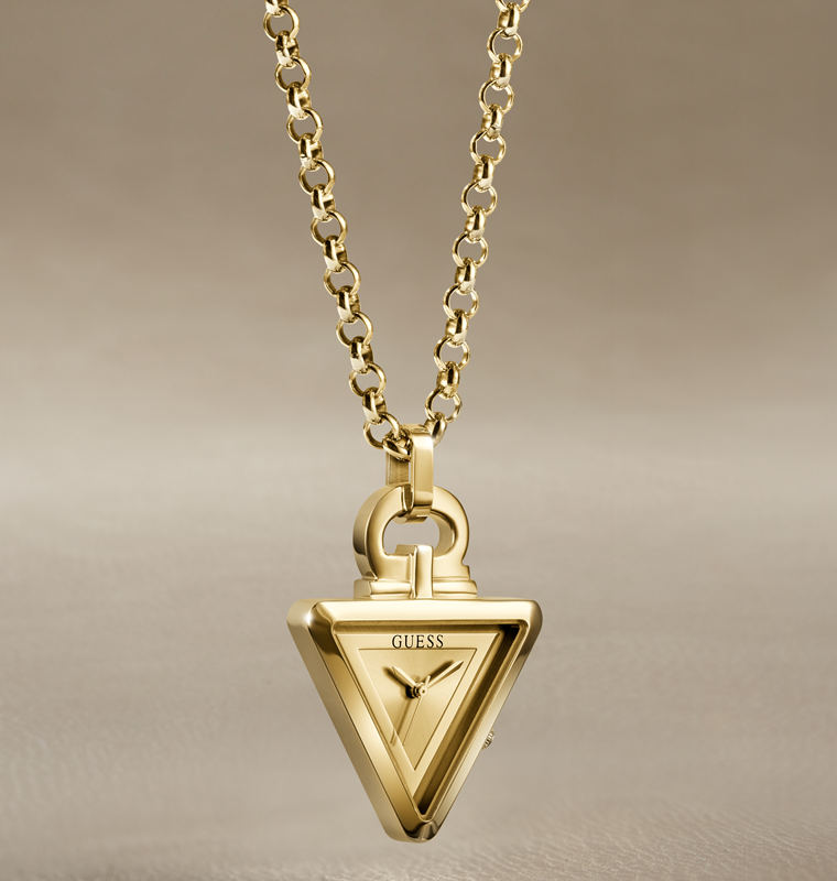 Gold-tone Guess triangle pendant necklace on a matching chain, displayed against a neutral beige background.