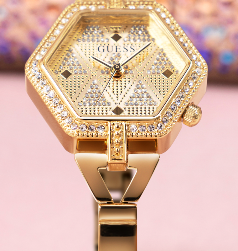gold hexagon shaped womens watch with stones on pink background