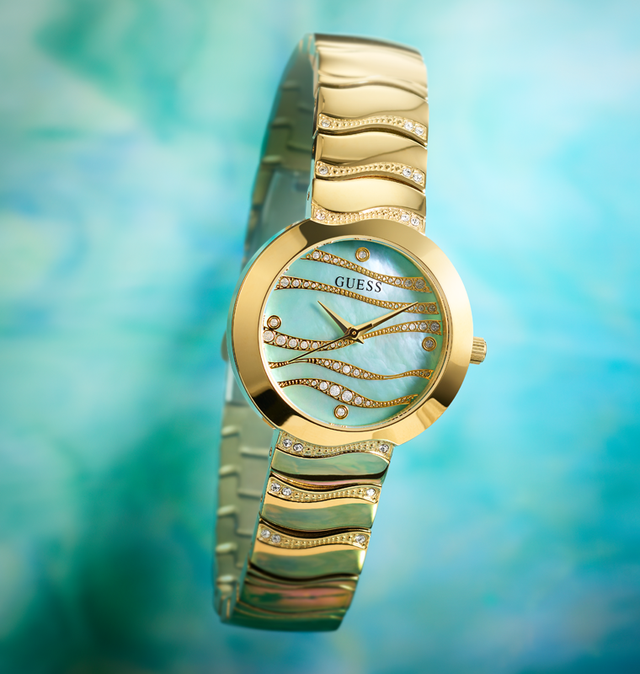 gold womens watch with crystals in small waves on band and mother of pearl aqua dial with subtle wave pattern on aqua ethereal background