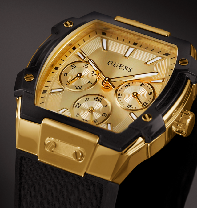 Gold and black Guess watch with detailed face on a dark background GW0945L2