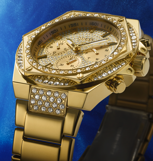 close up on mens gold watch with hexagonal shaped case and crystals on the dial and top ring and top of band