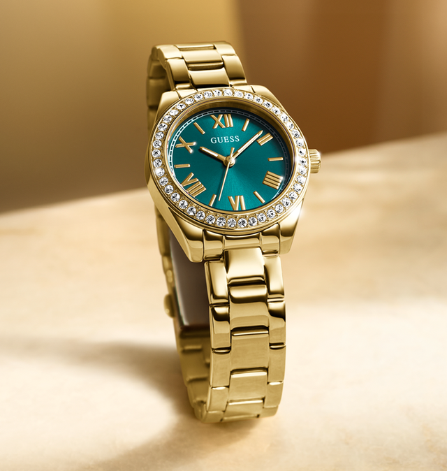 Gold watch with a green face on a beige background