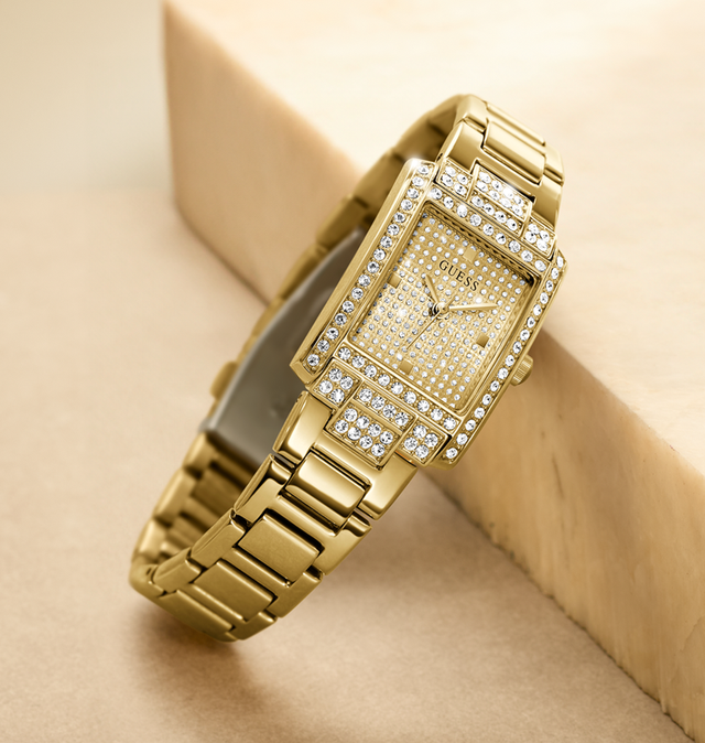 Gold watch with diamond accents on a beige background