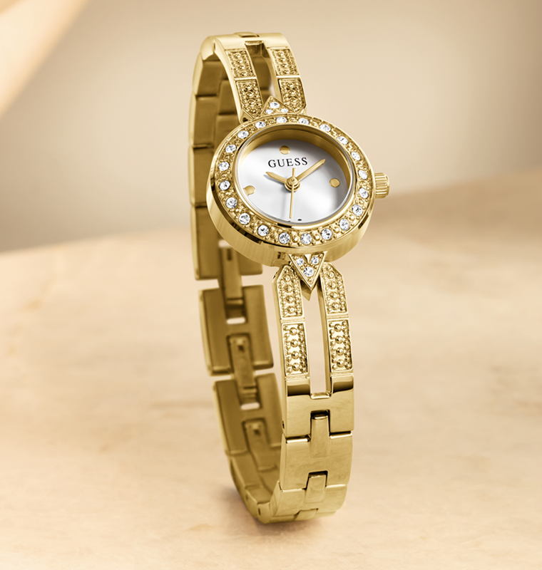 Gold watch with crystal accents on a beige background