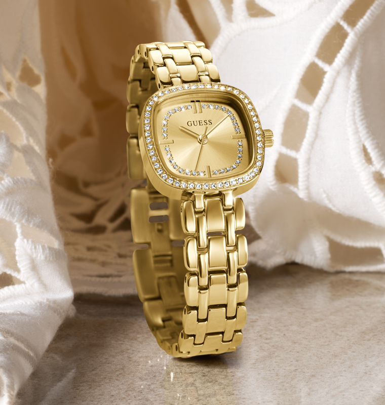 Gold watch with crystal-studded face on a textured surface