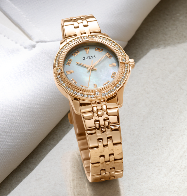Rose gold watch with gemstone accents on a light background