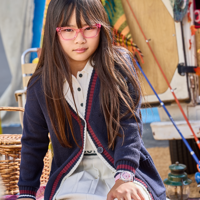 Young girl wearing glasses and a patterned cardigan in an outdoor setting