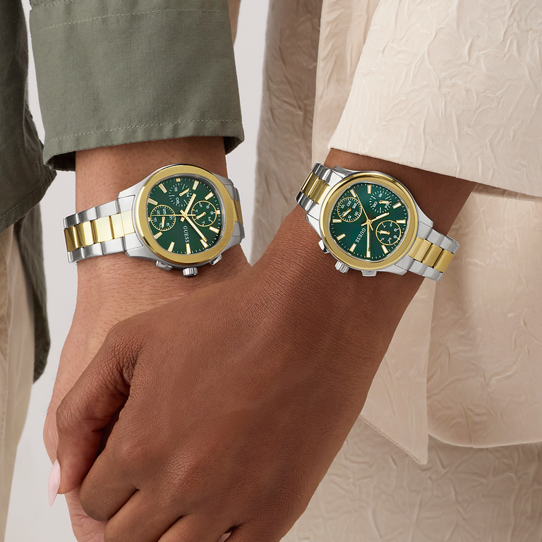 Two wrists wearing watches with green faces and gold accents on a neutral background