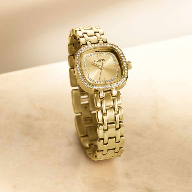 Gold GUESS watch with crystal accents on a beige background