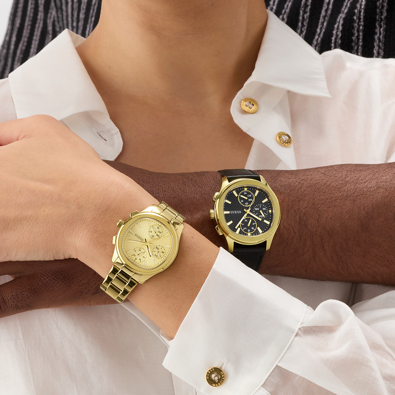 Two wrists wearing gold watches with a white shirt background