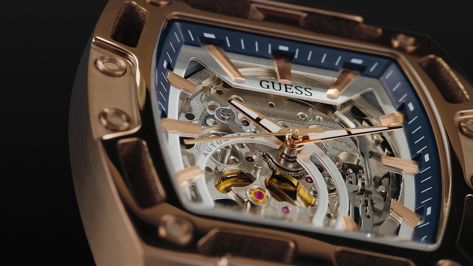 Close-up of a Guess watch with visible mechanical components on a dark background