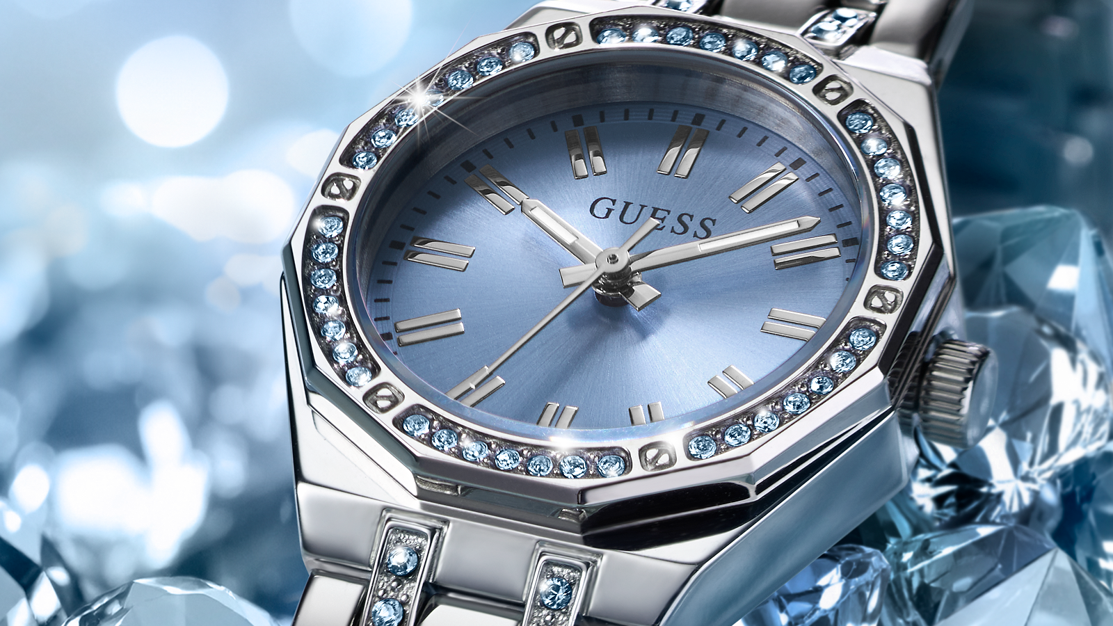 Silver Guess watch with blue face and gemstone accents on a blurred background