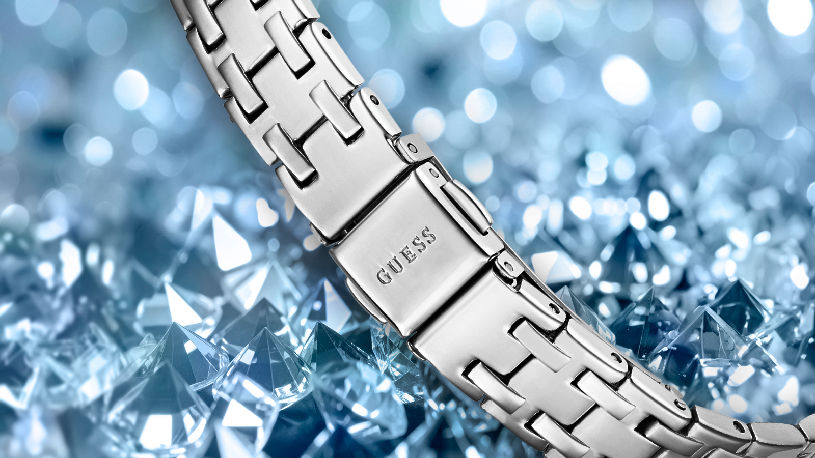 Silver bracelet with 'GUESS' branding against a blue crystal background pilot buckle
