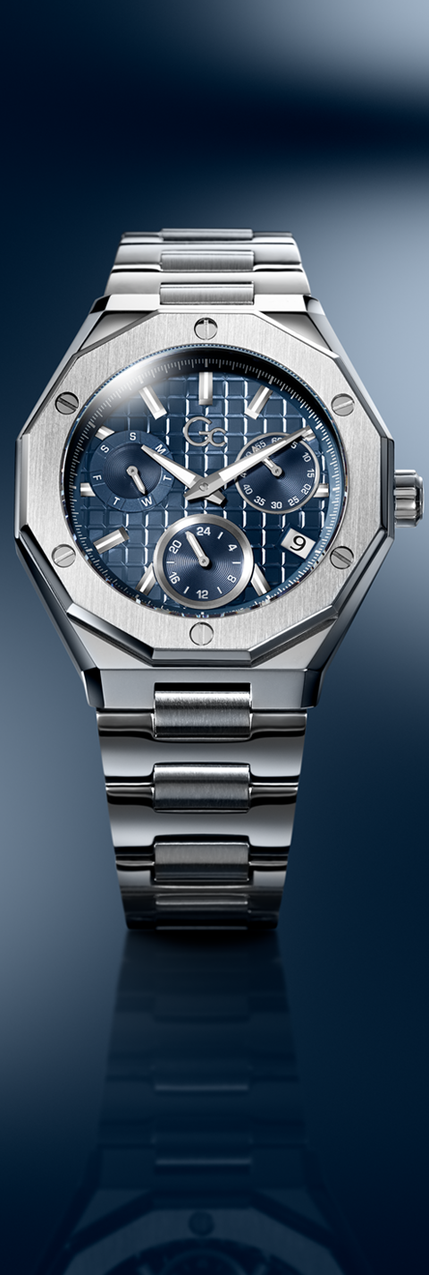 A luxury stainless steel wristwatch with an octagonal bezel, featuring a blue dial with white and silver geometric patterns, presented on a dark blue gradient background with a reflection below.