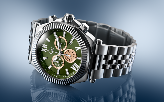 Silver watch with a green face on a reflective surface