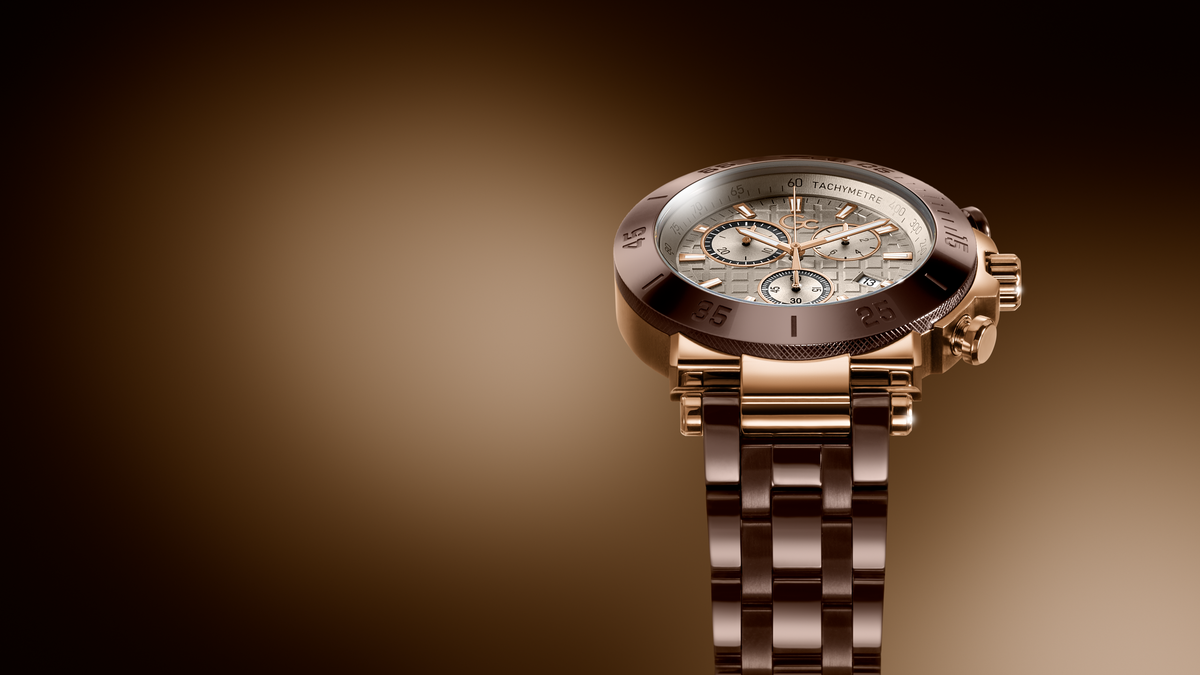 A luxury chronograph watch with a rose gold-tone metal case and link bracelet, featuring a white dial with multiple subdials and a dark bezel, set against a dark brown gradient background.