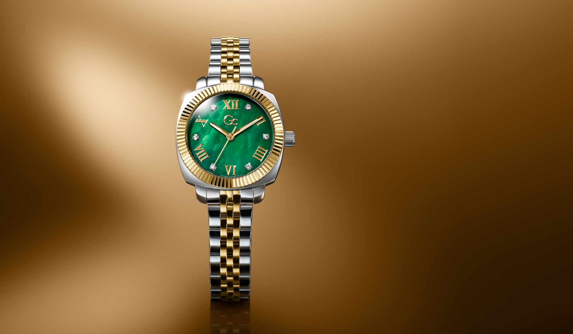 Gold and silver watch with a green face on a brown background