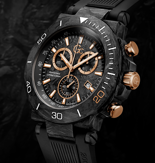 A close-up studio shot of a rugged chronograph watch with a black carbon-fiber-look case, black strap, and rose-gold-toned pushers and dial details, set against a dark textured background.