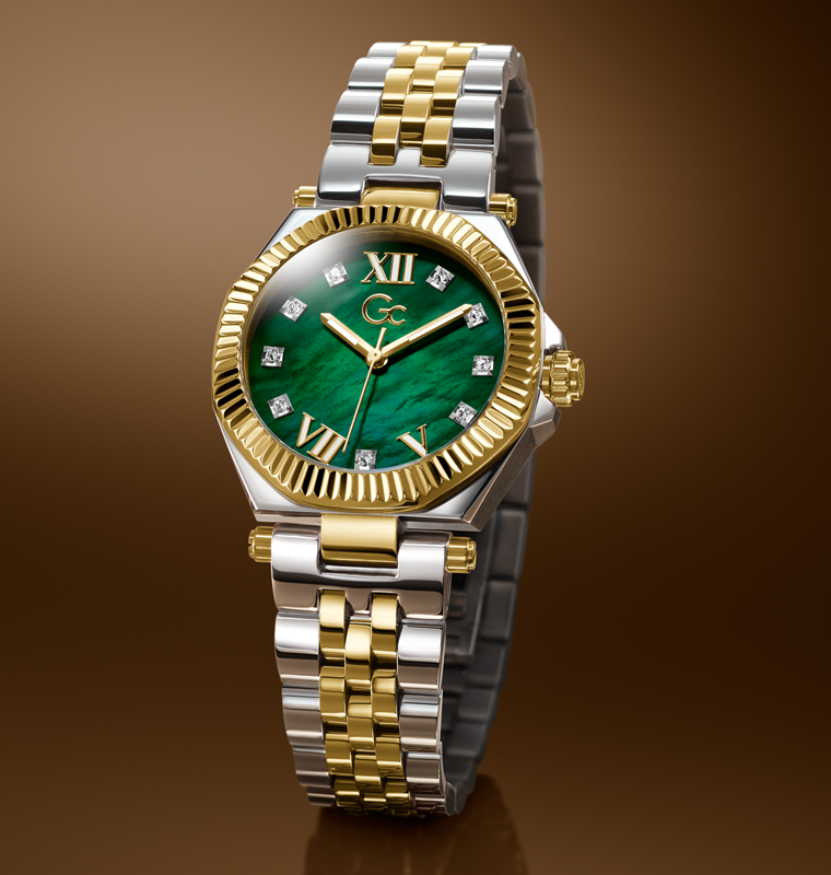 A luxury two-tone wristwatch with a green malachite dial, gold and silver stainless steel case and bracelet, and crystal hour markers, shown on a brown gradient background.