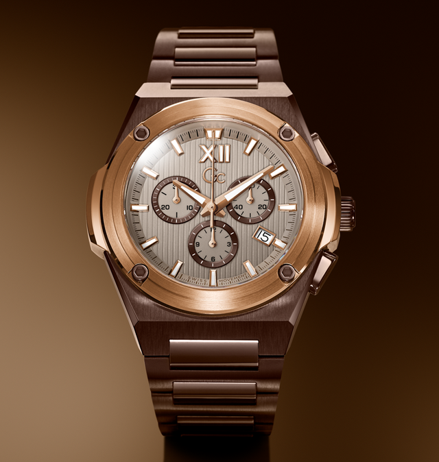 A luxury chronograph watch with a brushed rose gold-toned metal case and integrated bracelet, featuring a textured silver-gray dial with Roman numeral XII, three subdials, and a date window.