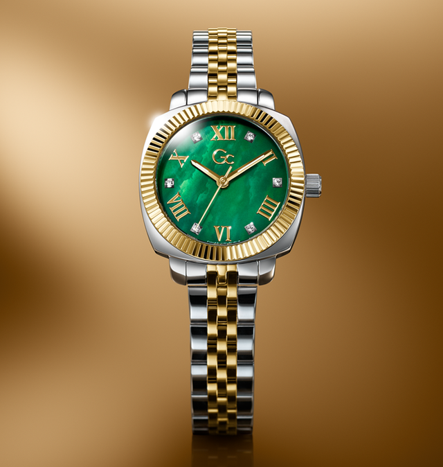 Luxury watch with green face and gold and silver band on a gold background