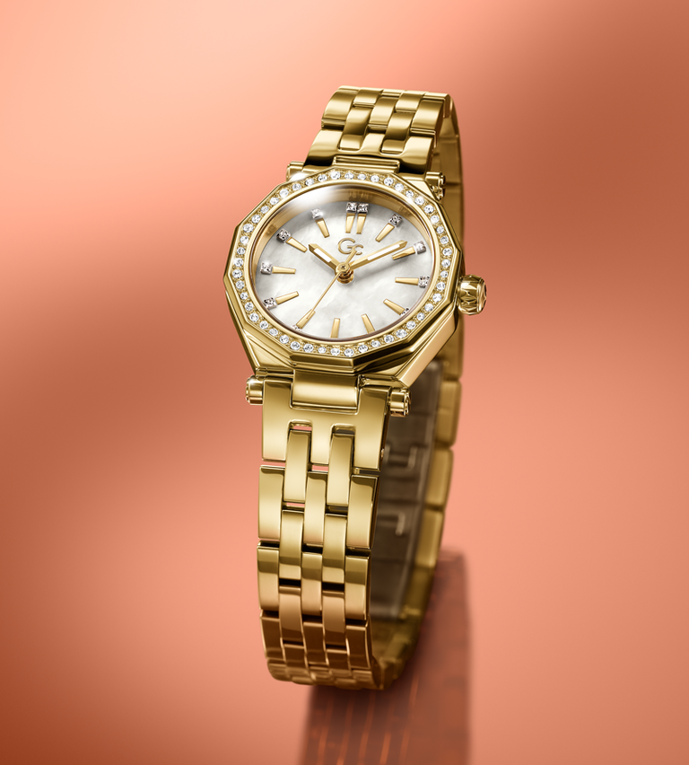Gold Gc wristwatch with a white face on a peach-colored background
