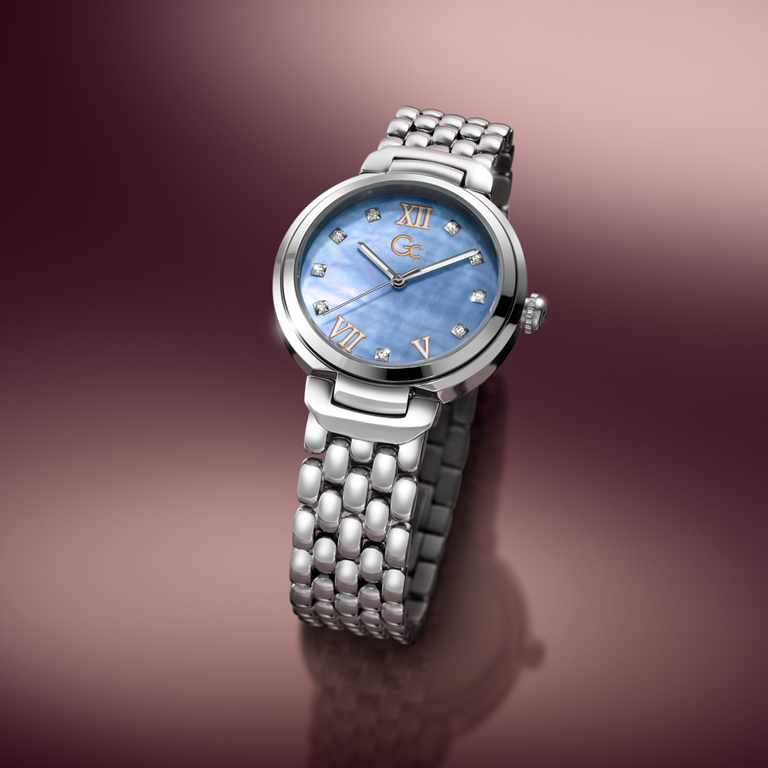 Silver Gc watch with a blue face on a gradient brown background