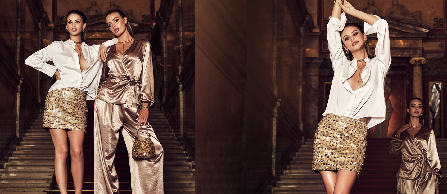 Two women in glamorous outfits posing in a luxurious setting.