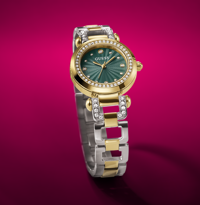 Gold and silver watch with green face on a pink background