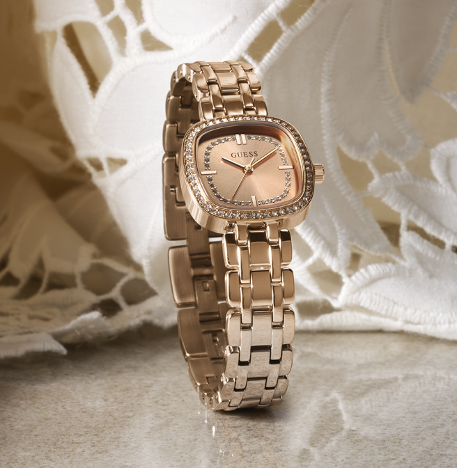 Rose gold watch with diamond accents on a textured surface