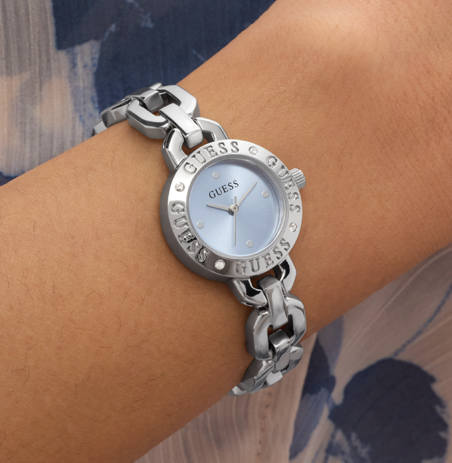 Silver Guess watch on a wrist with a blurred background