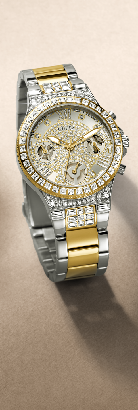 A luxury two-tone watch with a silver and gold-tone metal bracelet, a diamond-encrusted bezel, and a textured gold dial, shown on a neutral beige background.