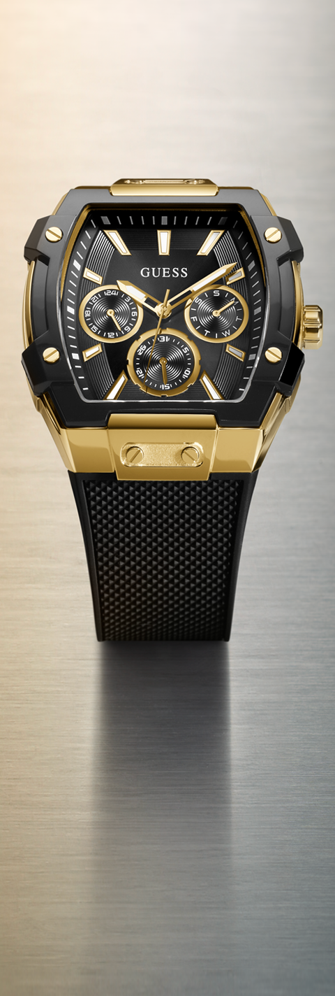 Gold and black watch with 'GUESS' branding on a metallic surface