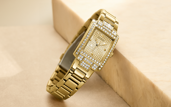 Gold wristwatch with diamond accents on a beige background