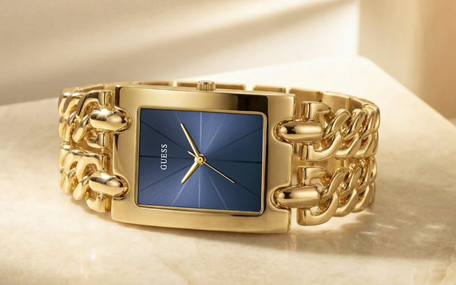 Gold chain-link watch with blue face on a beige background