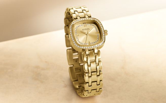 Gold watch with diamond-studded face on a beige background