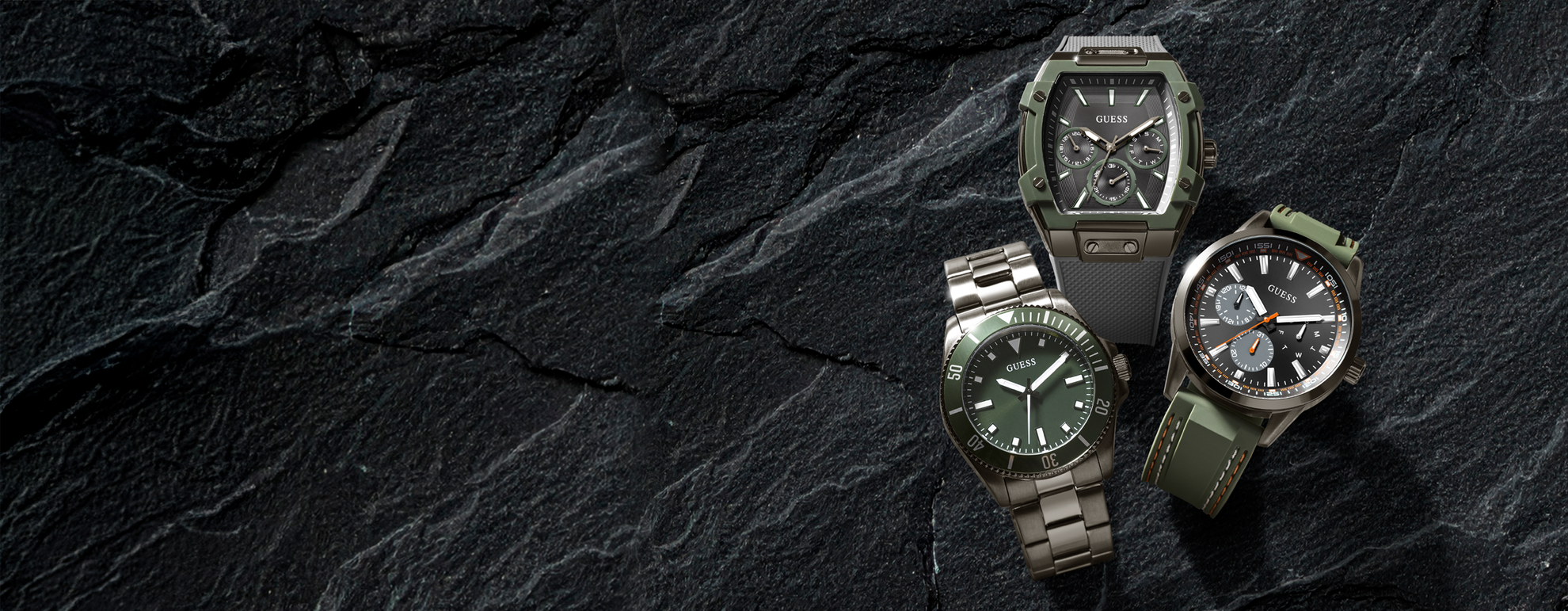 three mens GUESS sport watches on a stone background