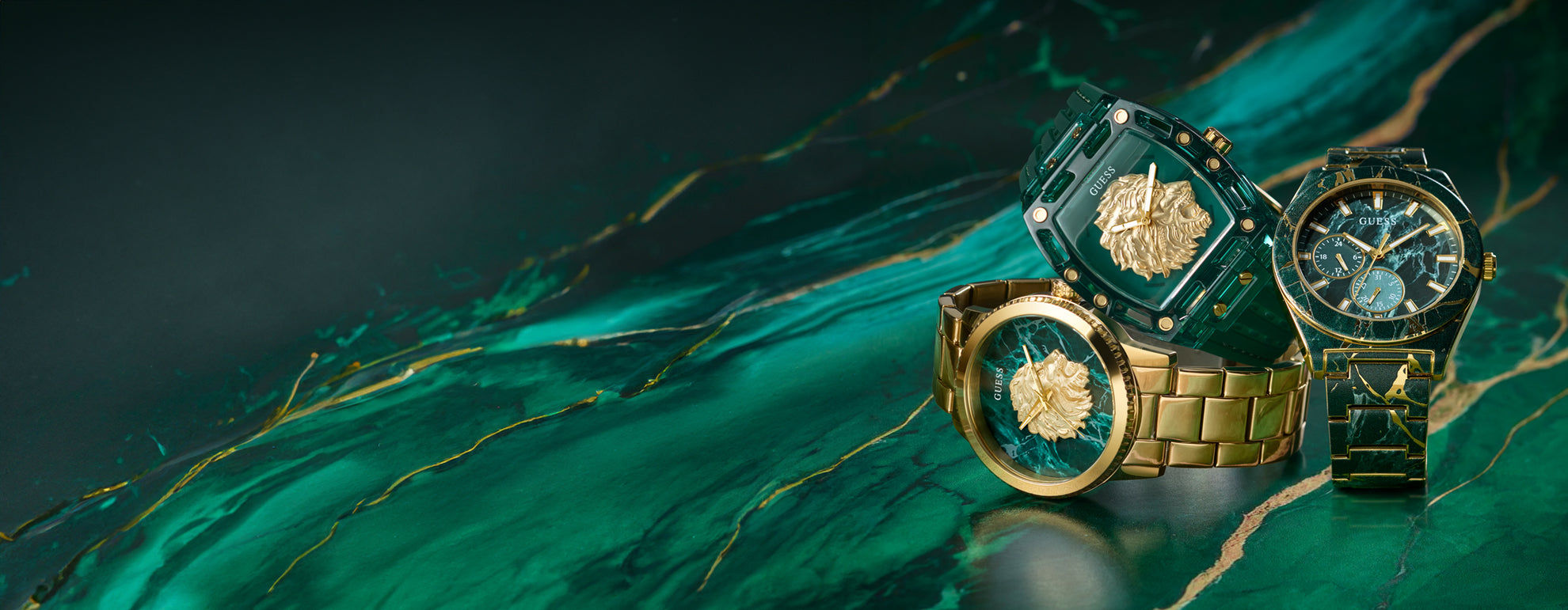 Three gold watches on a green and blue marbled surface