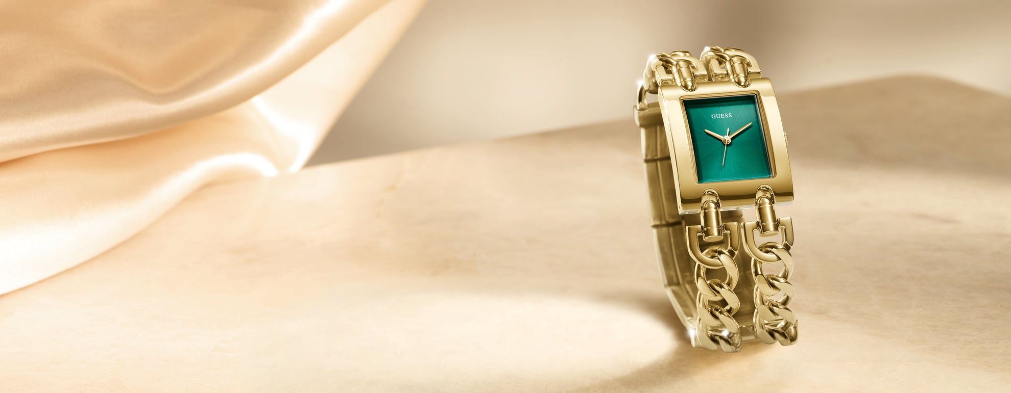 Gold watch with a green face on a beige fabric background