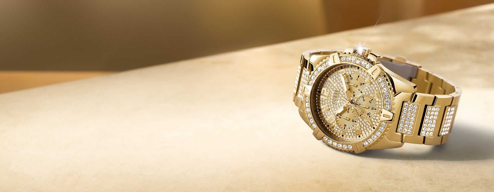 Gold wristwatch with diamond accents on a beige surface