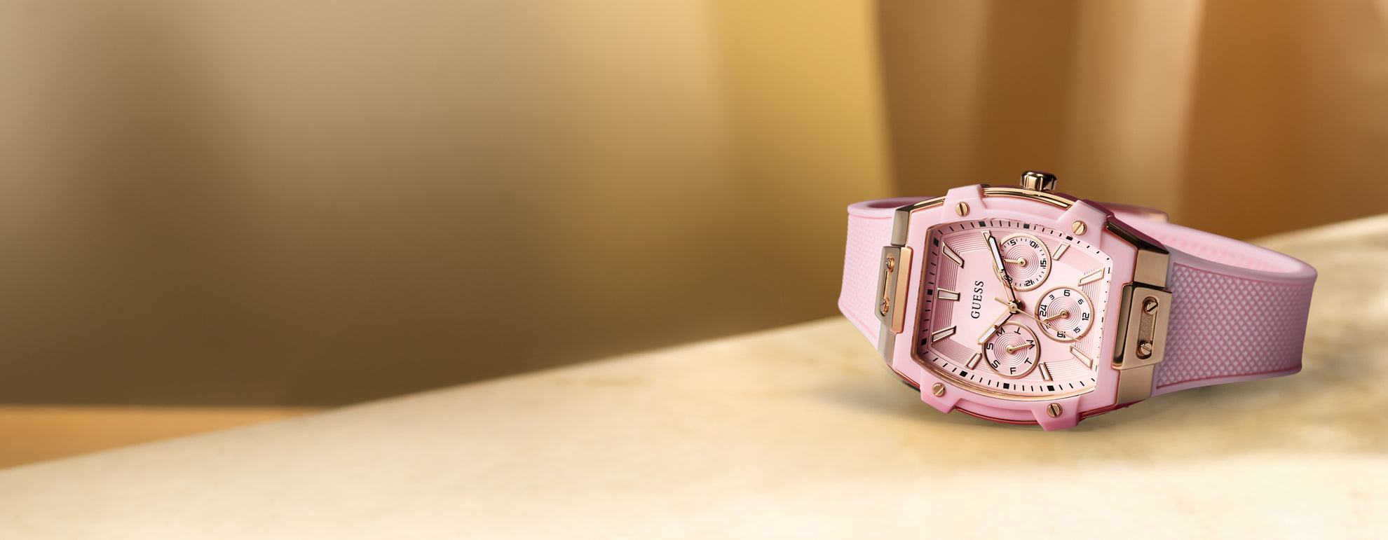 Pink wristwatch with a detailed face on a light surface with a blurred background