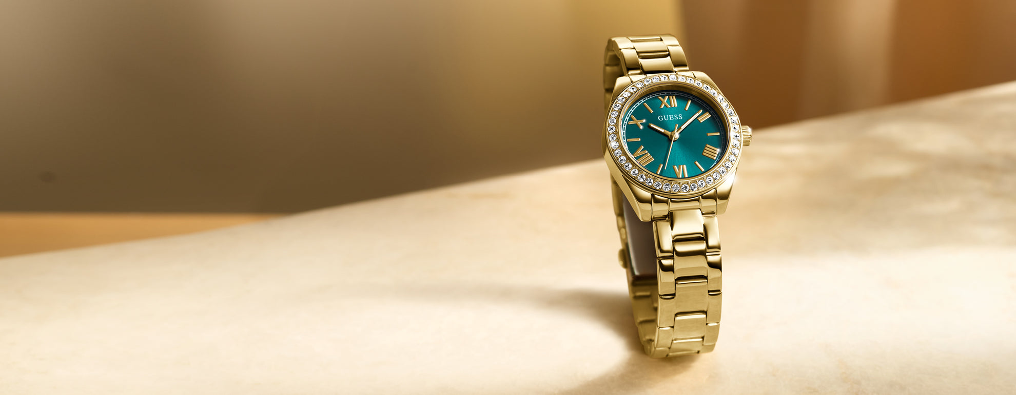 Gold wristwatch with a green face on a beige surface