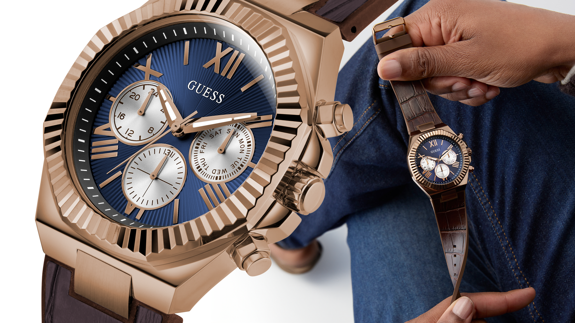 Rose gold watch with blue dial held by a person wearing a blue jacket.