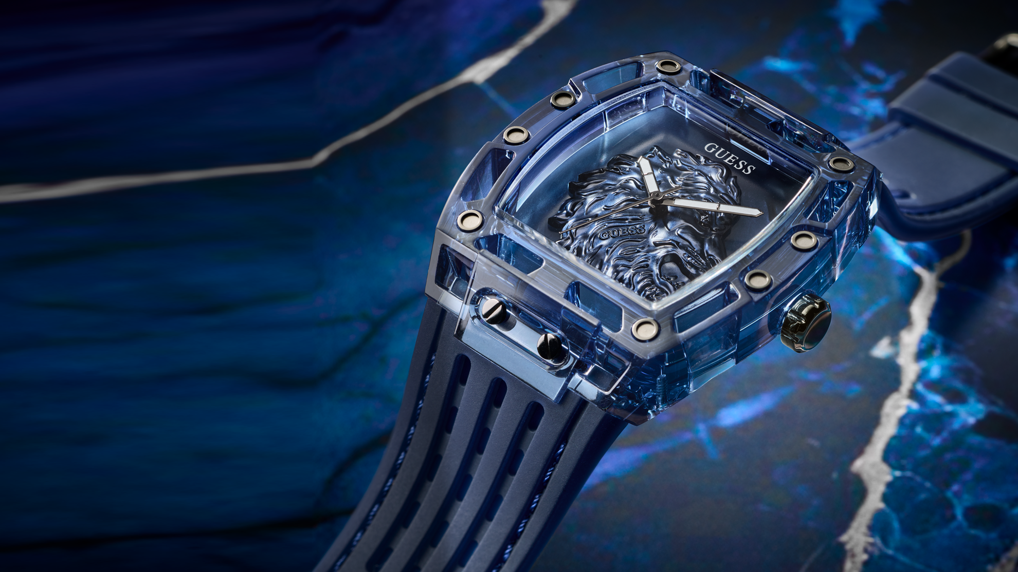 Blue Guess watch with transparent face on a dark blue background