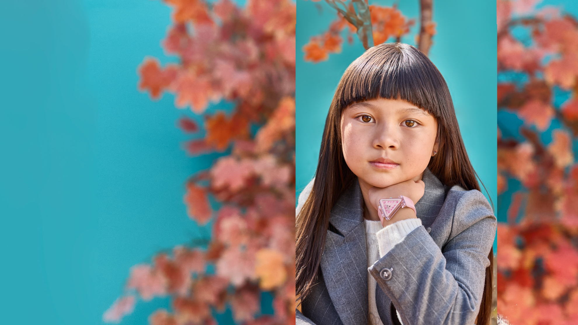Young girl in a gray coat with a blue background and autumn leaves wearing a pink guess triangle watch