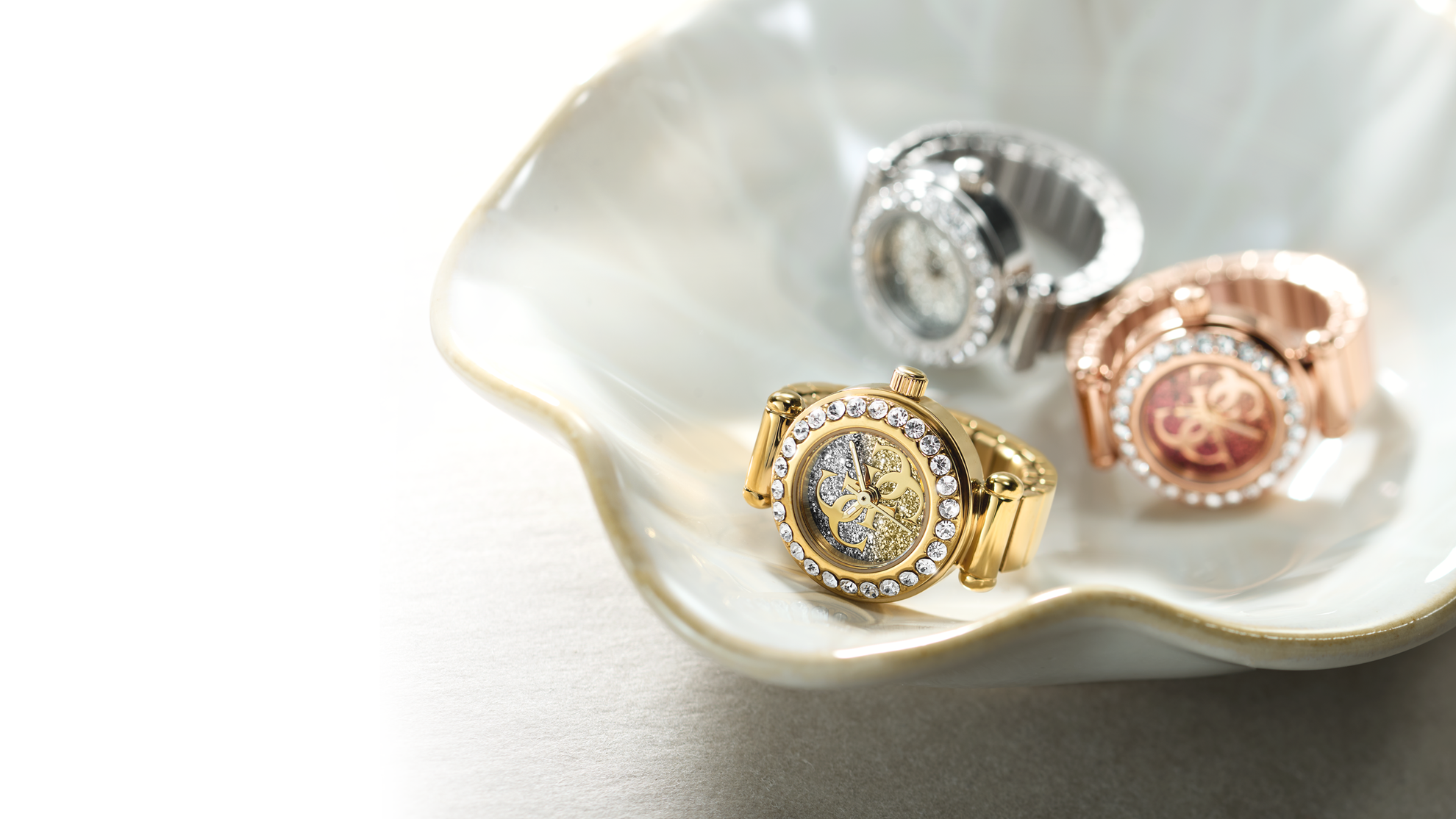 Three gold and silver jewelry watch rings on a white shell