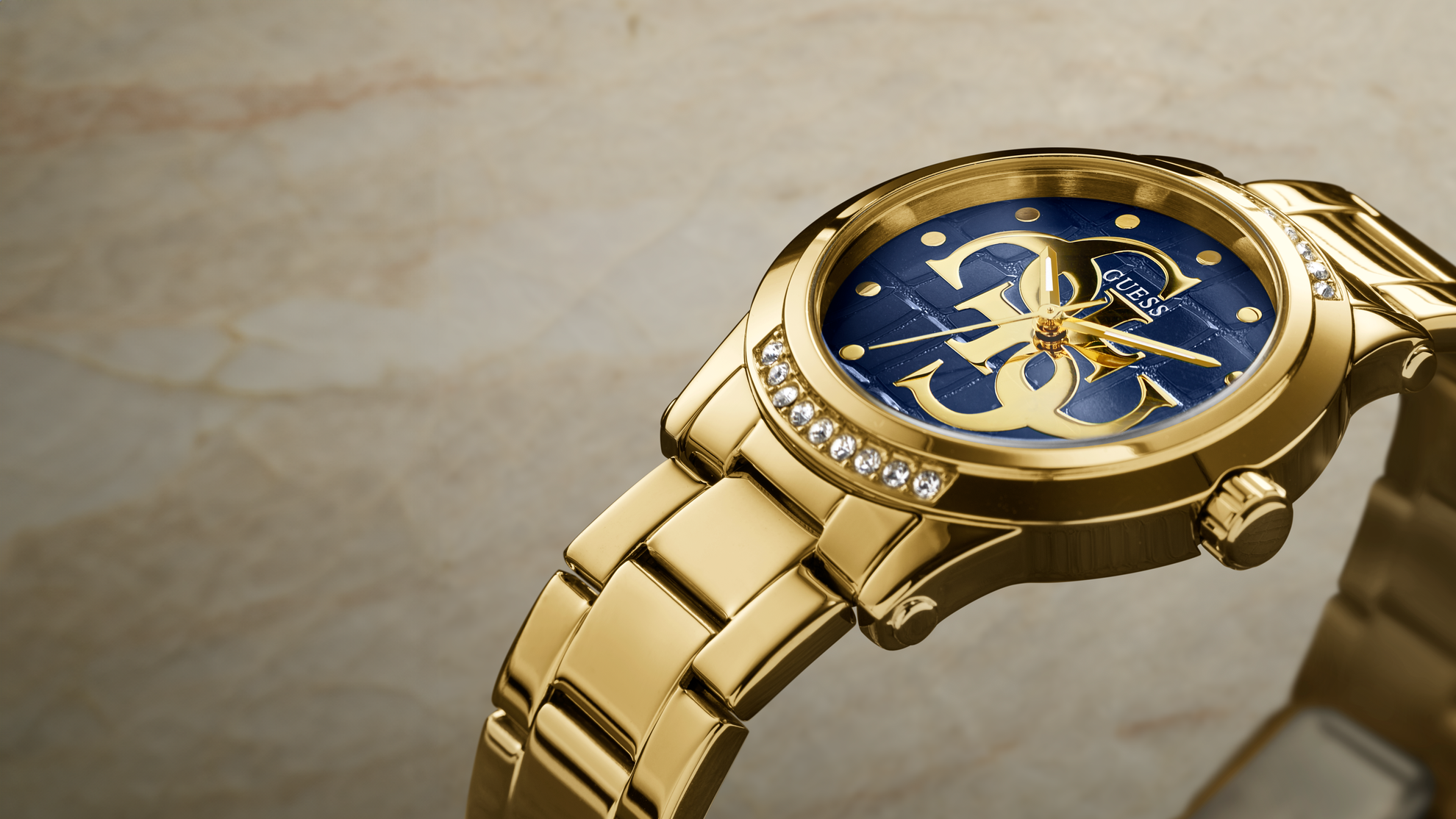 Gold wristwatch with a blue face on a beige background
